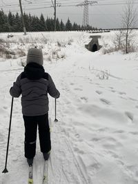 Rear view of girl standing on snow covered field