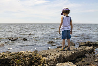 Little boy looking at polluted river from the shore, environmental concept