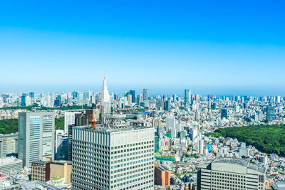 Aerial view of modern buildings in city against blue sky