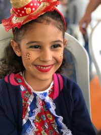 Cute girl with make-up looking away while sitting on chair