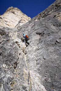 Low angle view of man climbing cliff