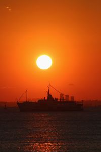 Silhouette ship on sea against orange sky during sunset