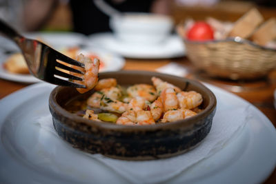Close-up of fork holding shrimps over plate