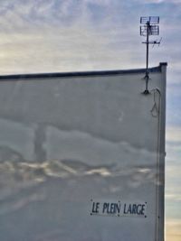 Close-up of sign on shore against sky