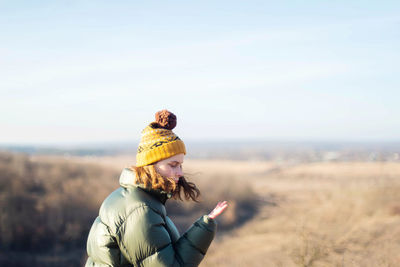 Rear view of woman standing on field against sky