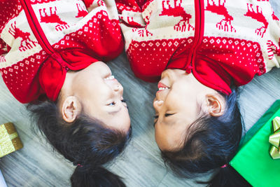High angle view of smiling sisters lying on floor at home