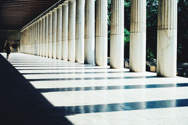 architecture, built structure, architectural column, indoors, in a row, column, the way forward, corridor, empty, pattern, shadow, sunlight, flooring, colonnade, repetition, diminishing perspective, tiled floor, incidental people, building exterior, building