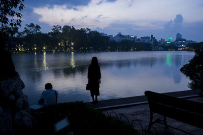 Silhouette of people overlooking lake