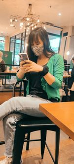 Woman using mobile phone while sitting on table