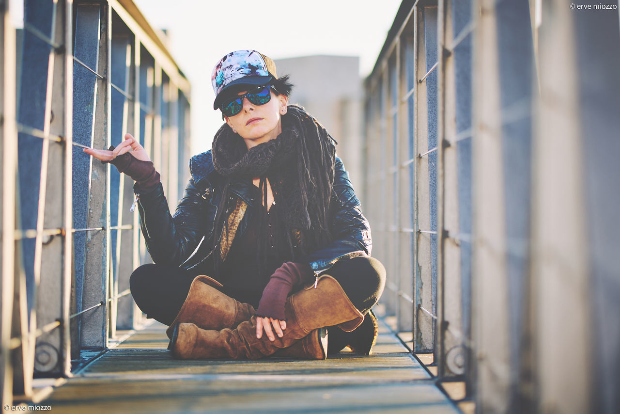 blue, adult, one person, men, architecture, lifestyles, spring, clothing, sports, cap, day, front view, full length, person, leisure activity, hat, nature, glasses, young adult, goggles, outdoors, fashion, sky, sitting, casual clothing, selective focus