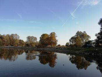 Reflection of trees in lake against blue sky