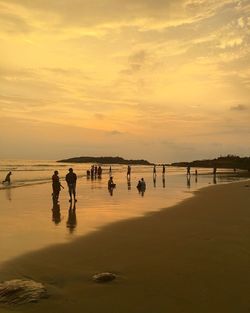 Silhouette people on beach against sky during sunset