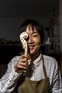 Young chinese violin maker at work in her workshop