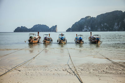 Boats moored at beach against clear sky