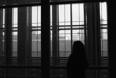 Silhouette woman standing against window
