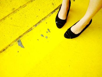 Low section of woman on yellow footpath