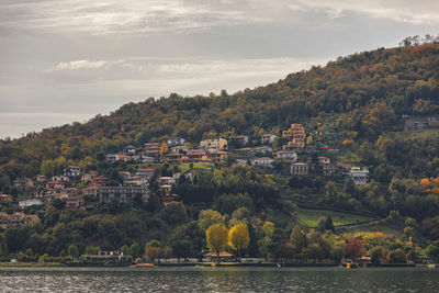 Scenic view of river by townscape against sky