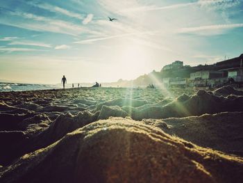 People at beach against sky during sunny day