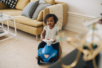 High angle view of girl riding toy car in living room at home