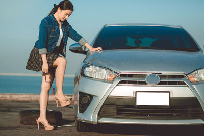 Full length of woman standing on car against sky