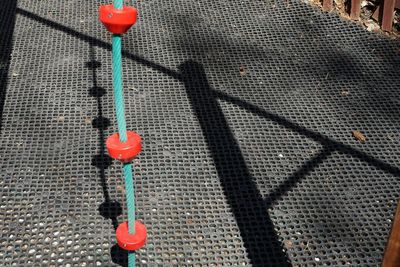 High angle view of red chain hanging on footpath