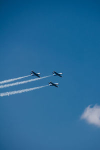 Low angle view of airplane flying against clear blue sky