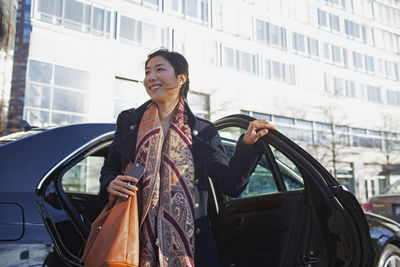 Young asian businesswoman getting out of car service limousine