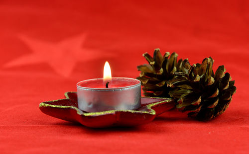 Close-up of tea light candles on red table