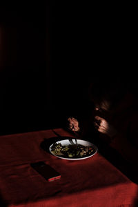 Portrait of woman holding coffee cup against black background