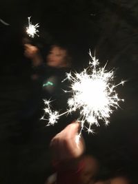 Low angle view of hand holding firework display at night