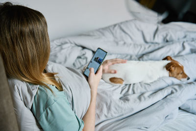 Side view of woman using mobile phone on bed at home