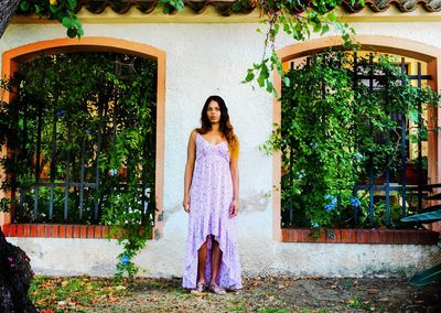 Young woman standing against plants