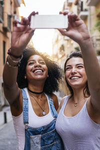 Happy friends taking selfie in city