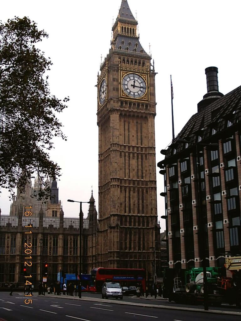 architecture, building exterior, built structure, city, car, tower, clock tower, transportation, land vehicle, street, clear sky, tall - high, travel destinations, low angle view, famous place, capital cities, travel, mode of transport, road, city street