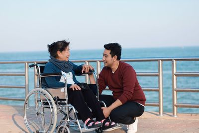 Senior woman with grandson sitting on wheelchair by sea