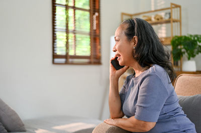 Young woman using mobile phone while sitting on sofa at home