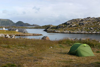 Tent on mountain by lake against sky