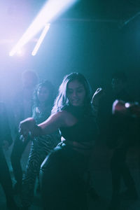 Young woman dancing against friends in background at nightclub