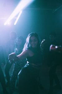 Young woman dancing against friends in background at nightclub