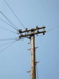 Low angle view of power lines against clear sky