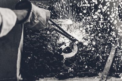 Cropped image of blacksmith heating metal over coal in workshop