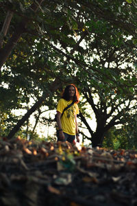 Woman standing by tree in forest