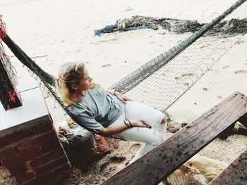 High angle view of mid adult woman relaxing on hammock at beach
