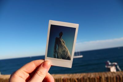 Person hand holding camera against sky