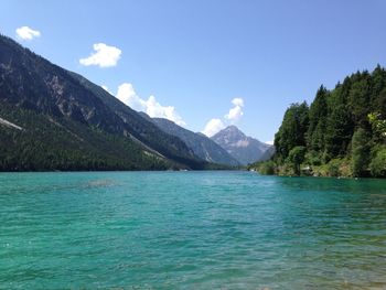 Scenic view of sea and mountains against blue sky