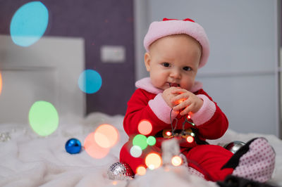 Portrait of cute baby holding lighting sitting on bed