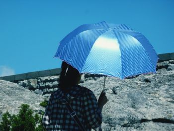 Rear view of man standing against blue sky