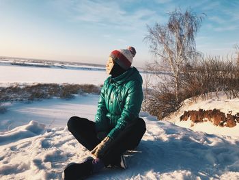 Man sitting on snow covered land