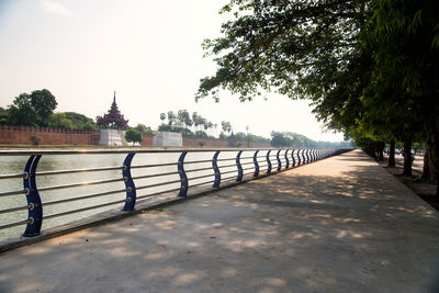 Empty footpath by railing against sky