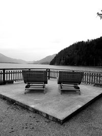 Empty bench in park against clear sky